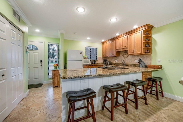 kitchen featuring open shelves, light stone countertops, white appliances, a peninsula, and a kitchen bar