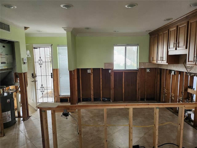 kitchen featuring crown molding, water heater, visible vents, light tile patterned flooring, and dark brown cabinets