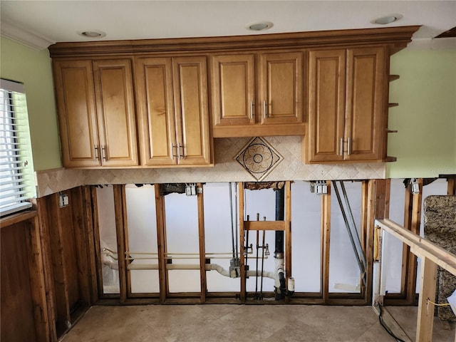 interior space featuring tasteful backsplash, brown cabinetry, and crown molding