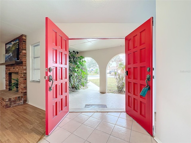 foyer featuring light wood-type flooring and a brick fireplace