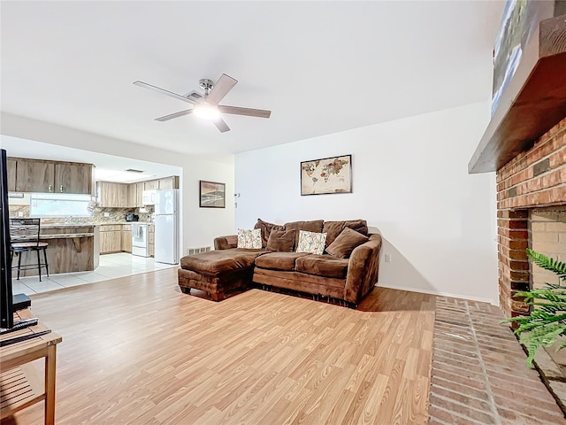 living room featuring light hardwood / wood-style floors, a brick fireplace, ceiling fan, and sink