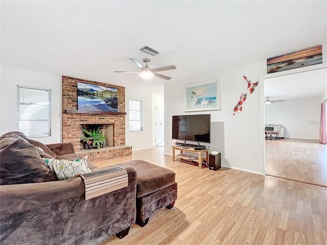 living room with ceiling fan, light hardwood / wood-style floors, and a fireplace