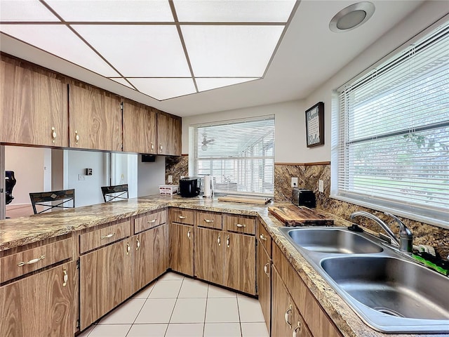 kitchen with tasteful backsplash, sink, light tile patterned floors, and a healthy amount of sunlight