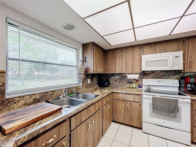 kitchen featuring white appliances, sink, light tile patterned floors, and tasteful backsplash