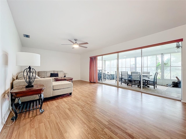 living room with light wood-type flooring, ceiling fan, and a healthy amount of sunlight