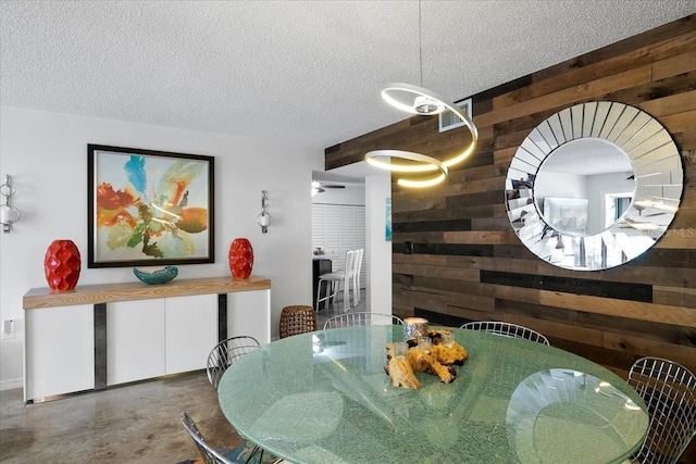 dining area with concrete flooring, a textured ceiling, a fireplace, and wooden walls