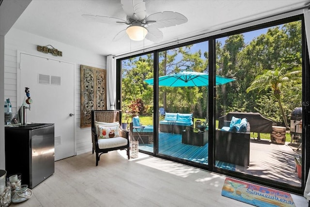 entryway featuring ceiling fan, expansive windows, and light hardwood / wood-style flooring