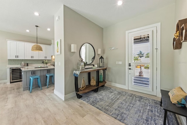 entrance foyer with plenty of natural light, light wood-type flooring, and wine cooler