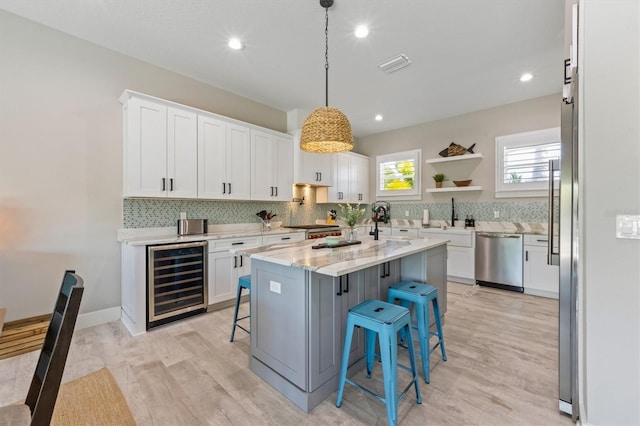 kitchen featuring dishwasher, wine cooler, light stone counters, a breakfast bar, and white cabinets