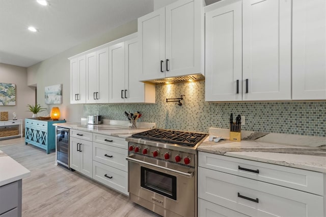 kitchen with backsplash, premium stove, white cabinets, and beverage cooler