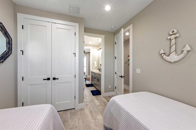 bedroom with light hardwood / wood-style floors, ensuite bath, and a closet