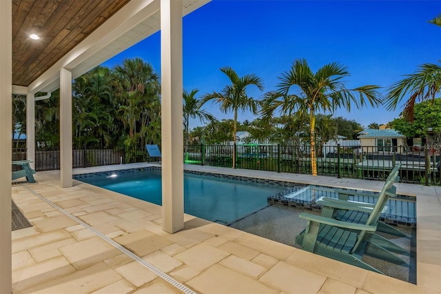 pool at dusk with an in ground hot tub and a patio area