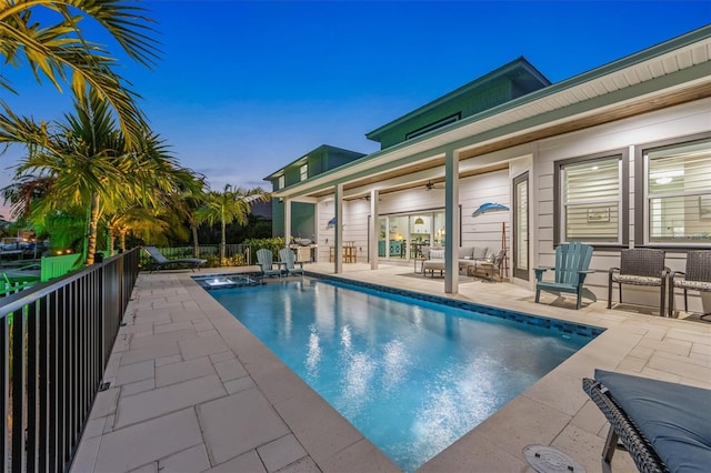 pool at dusk featuring ceiling fan, a patio, a jacuzzi, and an outdoor living space