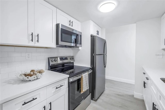 kitchen featuring tasteful backsplash, white cabinetry, light hardwood / wood-style flooring, and stainless steel appliances