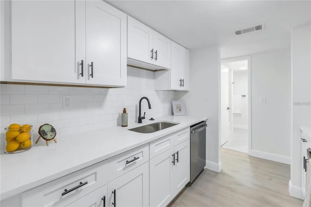 kitchen featuring white cabinets, tasteful backsplash, stainless steel dishwasher, and sink