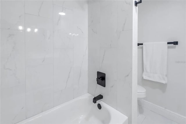 bathroom featuring tiled shower / bath combo and toilet