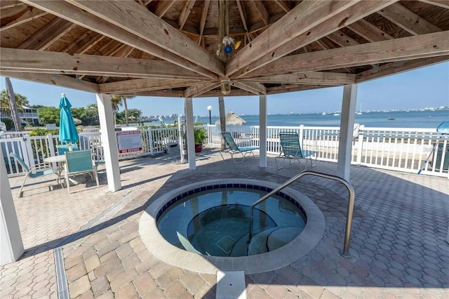 view of patio / terrace featuring a gazebo, a water view, and a hot tub