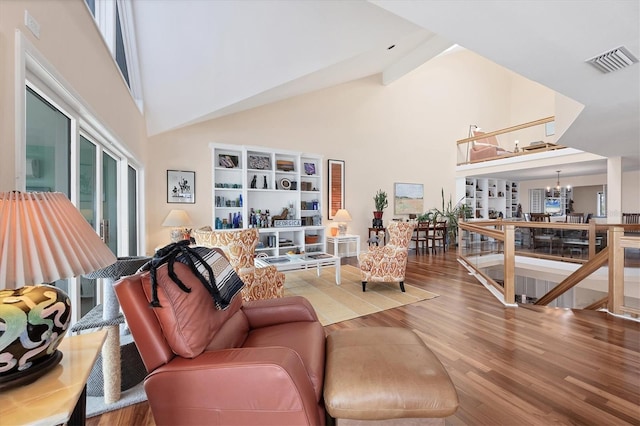 living room with beamed ceiling, wood-type flooring, high vaulted ceiling, and an inviting chandelier