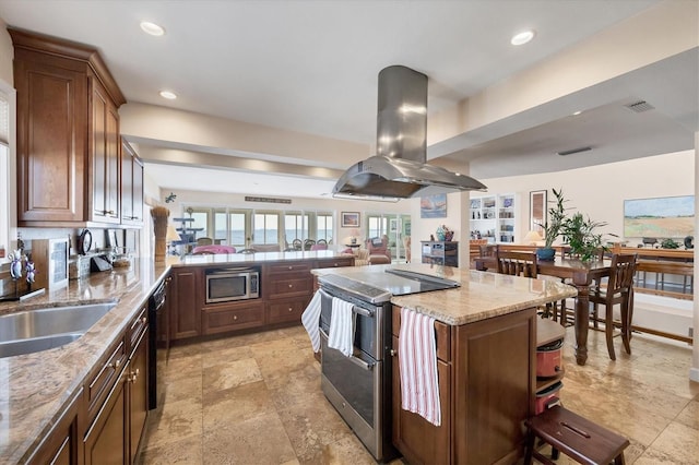 kitchen featuring island exhaust hood, appliances with stainless steel finishes, light stone countertops, sink, and a center island