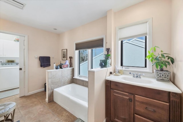 bathroom featuring a washtub, washer / dryer, and vanity