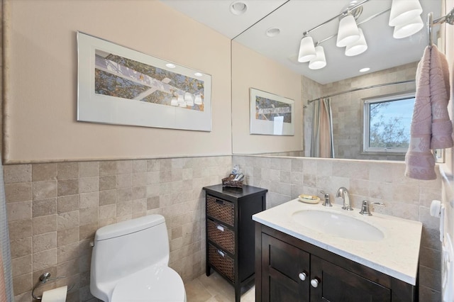 bathroom featuring walk in shower, vanity, toilet, and tile walls