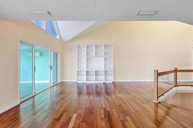 16 Tidy Island Blvd Unit 16, Bradenton, FL 34210 - empty room featuring hardwood / wood-style floors, a wall mounted air conditioner, baseboards, and high vaulted ceiling