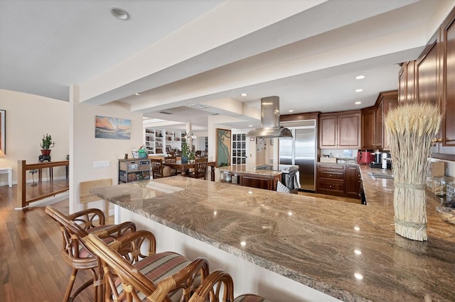 16 Tidy Island Blvd Unit 16, Bradenton, FL 34210 - kitchen featuring island range hood, light stone countertops, a breakfast bar, a peninsula, and wood finished floors