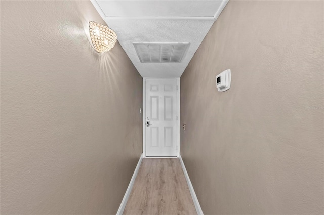 hallway with a textured ceiling and light wood-type flooring