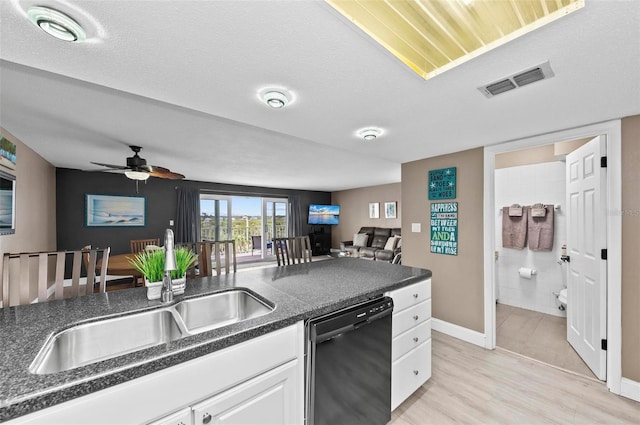 kitchen featuring a textured ceiling, light wood-type flooring, white cabinetry, and black dishwasher