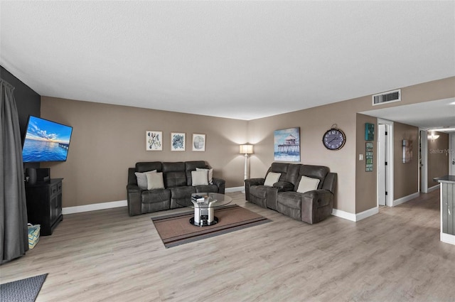 living room with a textured ceiling and light wood-type flooring