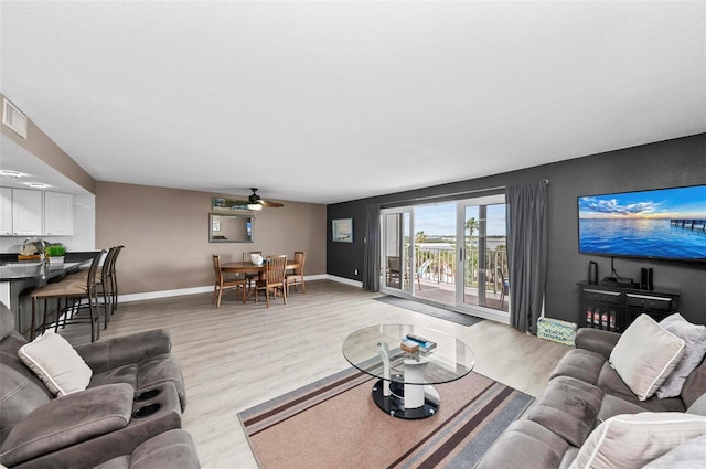 living room featuring ceiling fan, sink, and light wood-type flooring