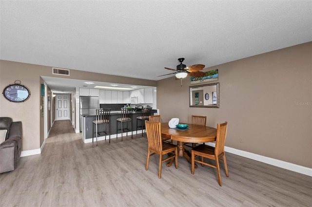 dining room featuring ceiling fan, light hardwood / wood-style floors, and a textured ceiling