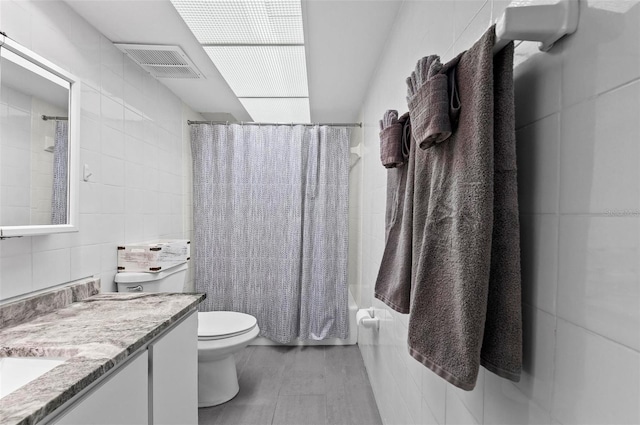 full bathroom featuring vanity, toilet, tile walls, and shower / tub combo with curtain