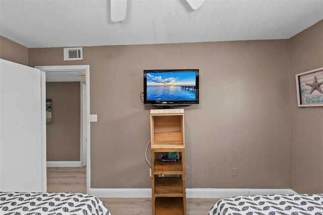 bedroom with ceiling fan, a textured ceiling, and light wood-type flooring