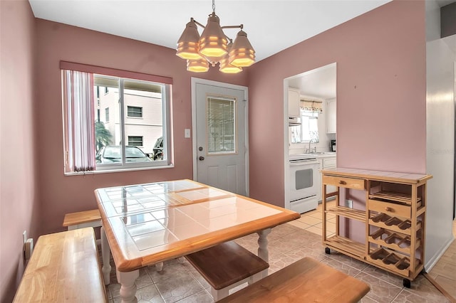 dining area featuring light tile patterned flooring, a notable chandelier, a healthy amount of sunlight, and sink