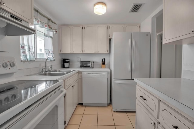 kitchen featuring white cabinetry, white appliances, sink, and light tile patterned floors