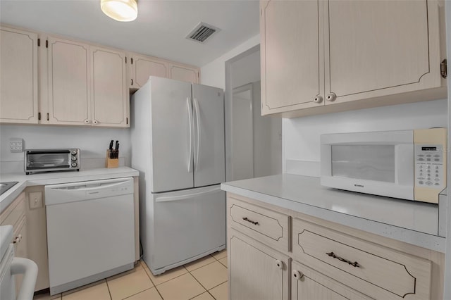 kitchen featuring light tile patterned floors, white appliances, and light brown cabinetry