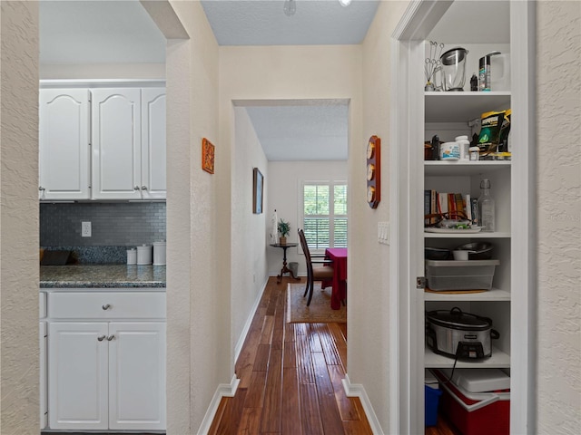 hallway with dark hardwood / wood-style floors and a textured ceiling