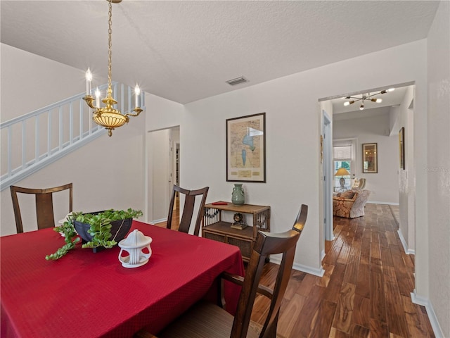 dining space featuring a chandelier, a textured ceiling, and dark wood-type flooring