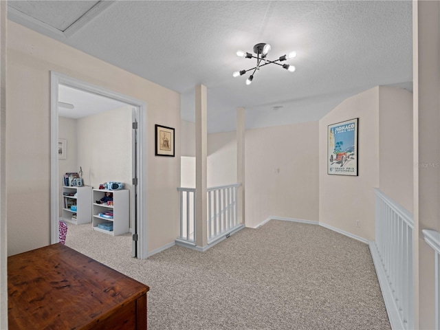 hallway with a notable chandelier, carpet floors, and a textured ceiling