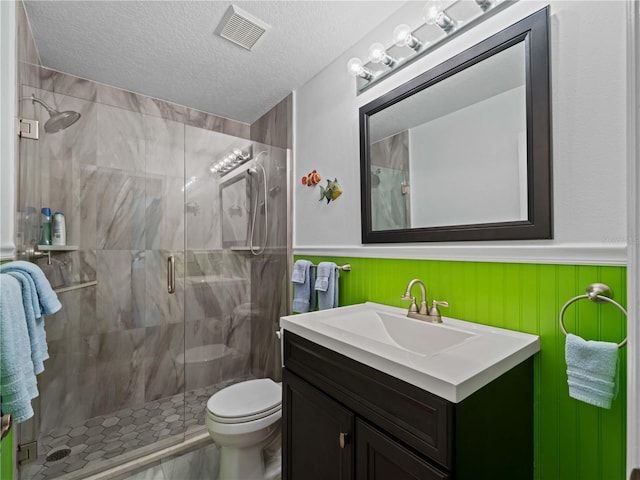 bathroom with a shower with door, vanity, a textured ceiling, and toilet