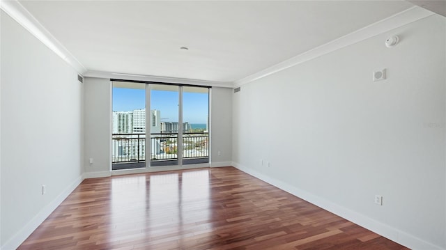 spare room with hardwood / wood-style flooring, ornamental molding, and floor to ceiling windows