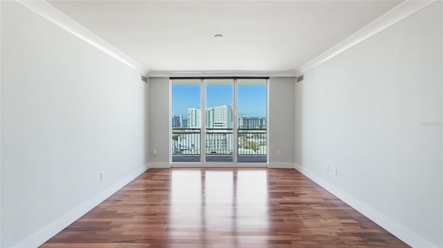 unfurnished room with dark wood-type flooring, ornamental molding, and expansive windows