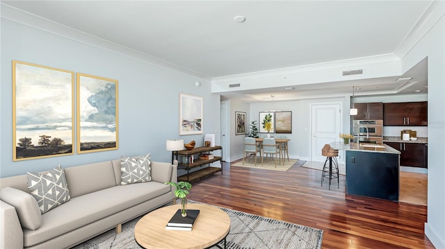 living room with dark hardwood / wood-style flooring, sink, and ornamental molding