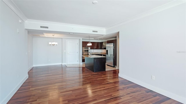 unfurnished living room featuring sink, crown molding, dark hardwood / wood-style floors, and a chandelier