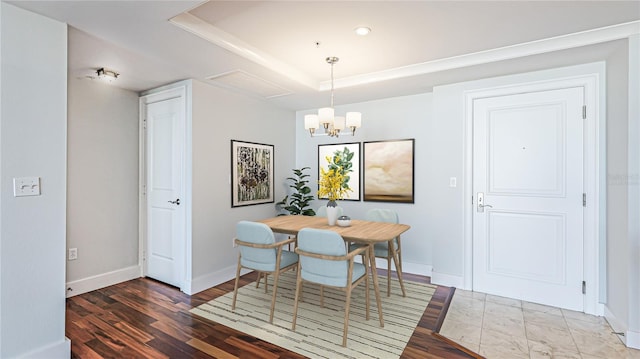 dining space featuring dark hardwood / wood-style flooring, a raised ceiling, and a notable chandelier