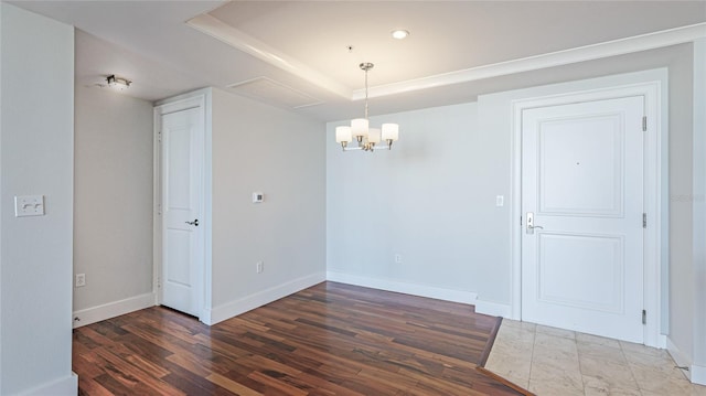 unfurnished room featuring a raised ceiling, dark wood-type flooring, and a chandelier