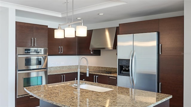 kitchen with sink, appliances with stainless steel finishes, light stone countertops, decorative light fixtures, and exhaust hood