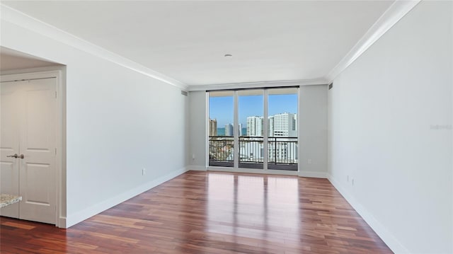 empty room featuring crown molding, wood-type flooring, and floor to ceiling windows