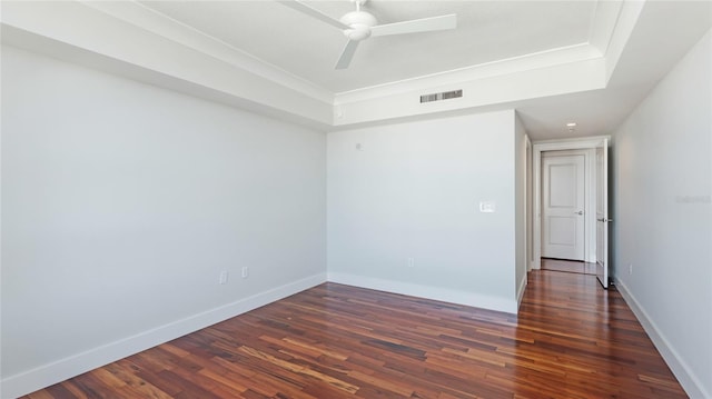 unfurnished room with a raised ceiling, dark hardwood / wood-style floors, and ceiling fan